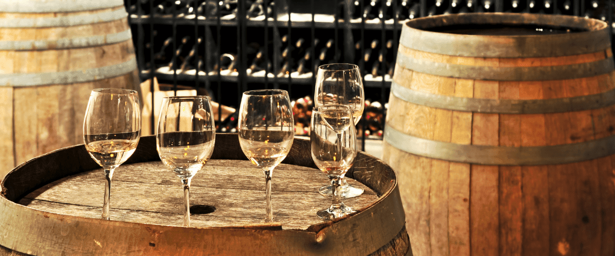 image of a wine cellar with barrels, bottles and glasses